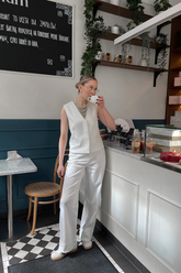 a lady in a white vest and a pair of white pants